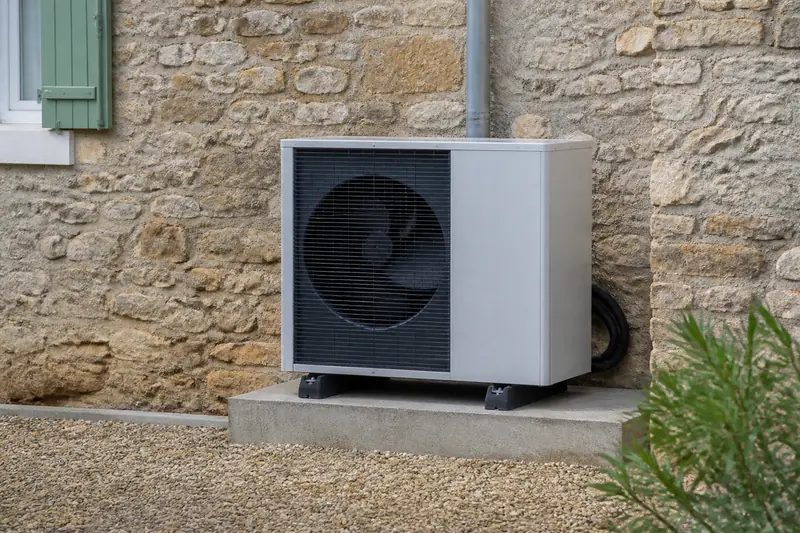 Unité extérieure de pompe à chaleur air-eau contre le mur d'une maison à Louvigny
